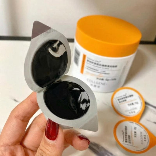 Face mask sachets with glossy black gel; jar with orange lid on counter