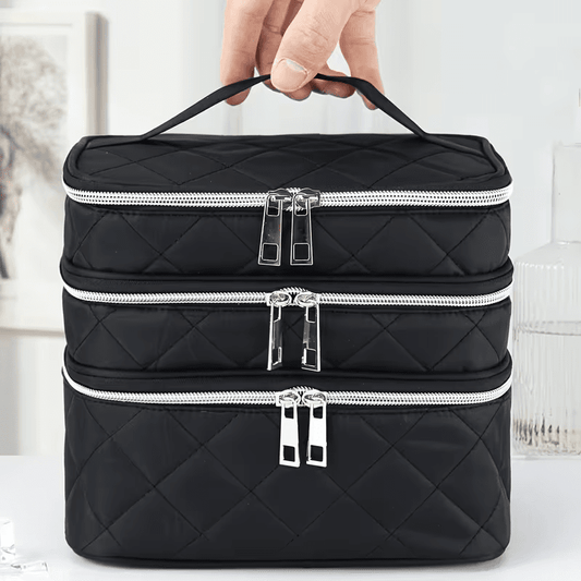 Black quilted cosmetic bag with three stacked zipper pockets and carry handle.