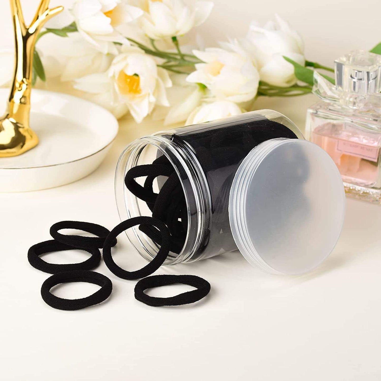 Black elastic hair ties scattered from clear jar with screw-top lid