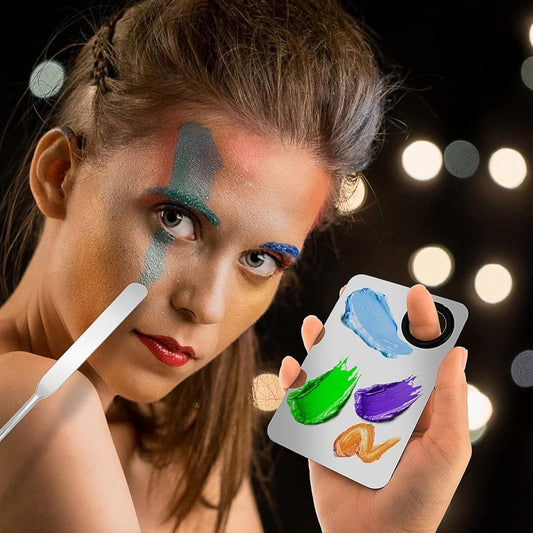 Makeup mixing palette with colorful paint swatches and metal spatula, held in hand