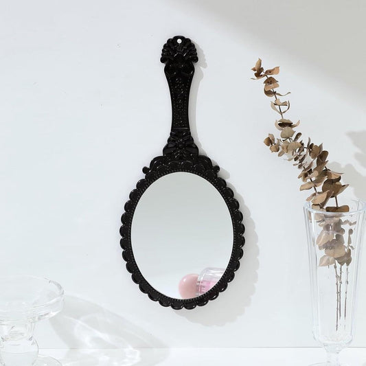 Black oval travel hand mirror with embossed floral detailing and long handle