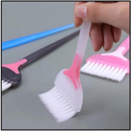 Hair dye applicator brush held by hand, pink handle and white bristle head