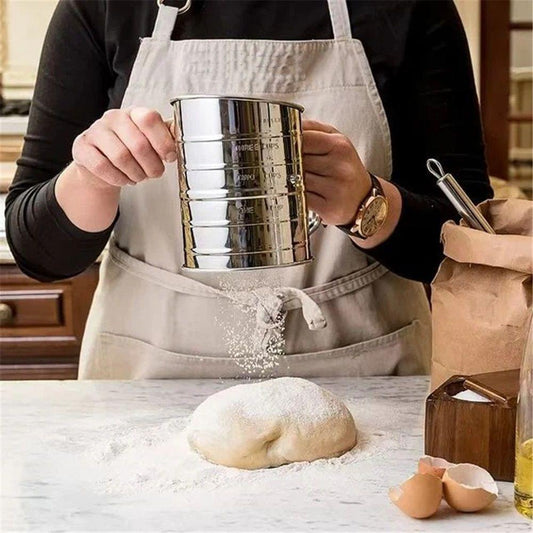 Rotary flour sifter held above dough, fine mesh drum with crank handle