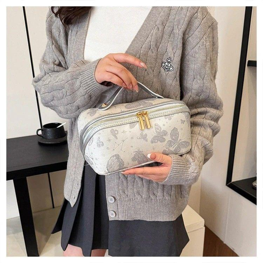Vintage-style makeup bag being held; gold zipper top and light gray floral print