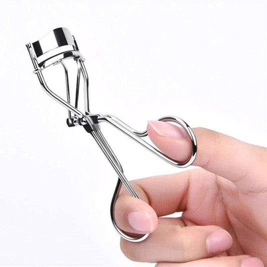 Silver eyelash curler held in hand, rounded lash clamp with black pad