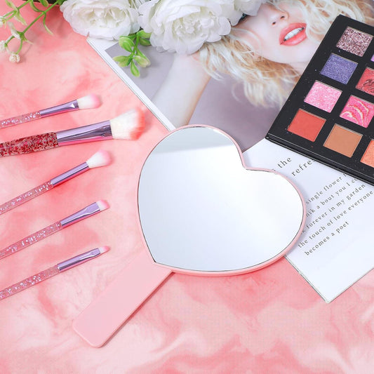 Heart-shaped handheld mirror with pink handle, reflecting a white mirror surface
