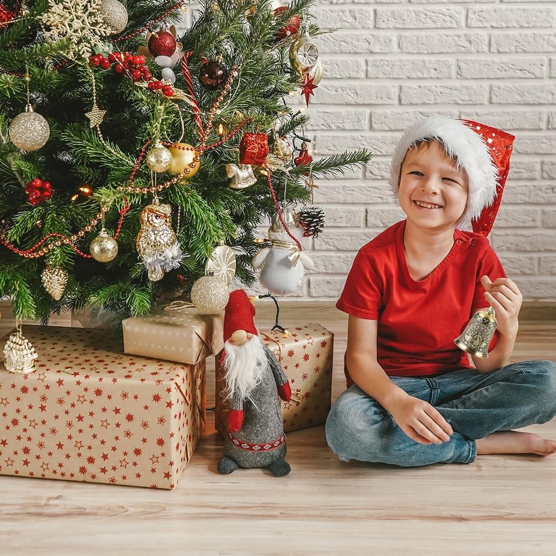 Ornate brass handbell held by a smiling child near Christmas decor