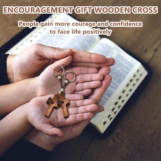 Wooden cross keychain with metal key ring held in a hand