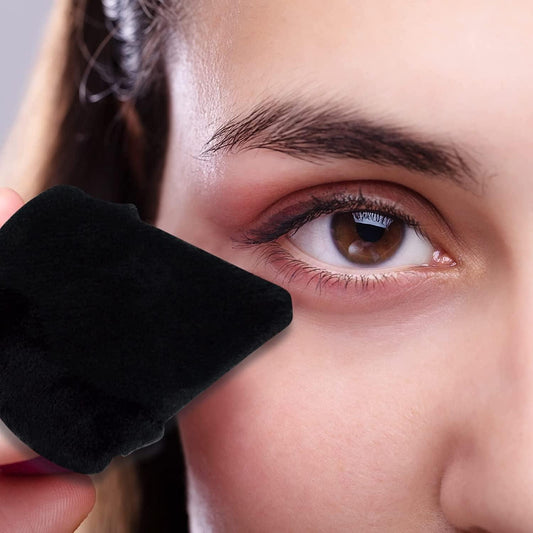 Black triangle powder puff near eye, used for makeup blending and setting