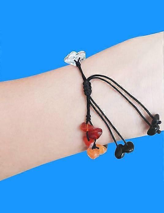 Gemstone bead bracelet on wrist with black cord and red, orange, and dark charms