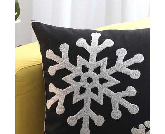 Black throw pillow cover with oversized white snowflake motif, close-up