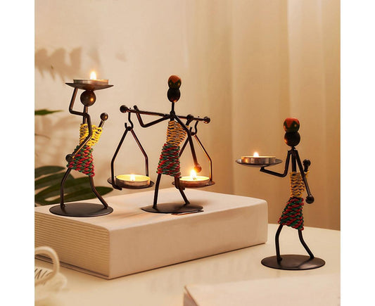 Set of abstract iron candle holders with small metal figures and glowing lantern candles