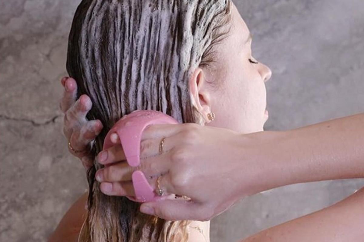 Pink scalp massager brush being used on wet hair for gentle massage