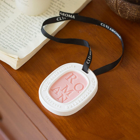 Hanging wax tablet pendant with white frame and pink translucent center on black ribbon.