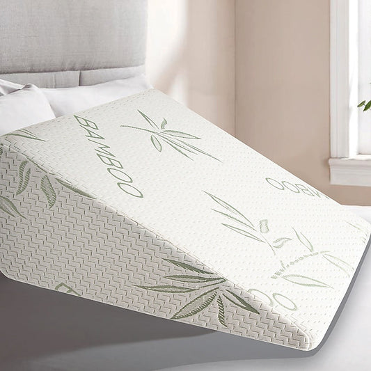 White wedge pillow with green bamboo print on a bed surface