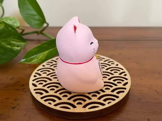 Pink seated Maneki Neko cat figurine on patterned round base