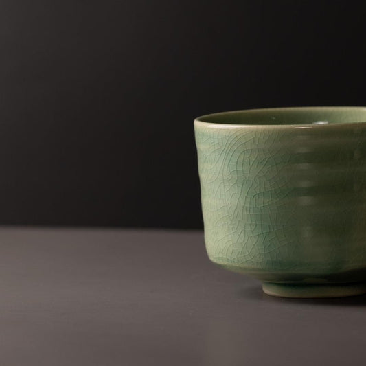 Jade green ceramic matcha tea bowl with crackle pattern and rounded base