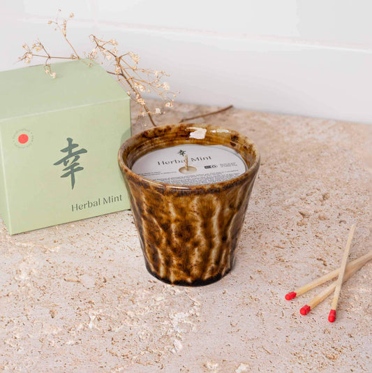 Amber ceramic scented candle with white wax beside mint-colored gift box