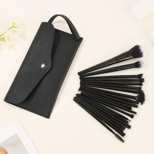 Black travel pouch holding assorted makeup brushes with dense synthetic bristles