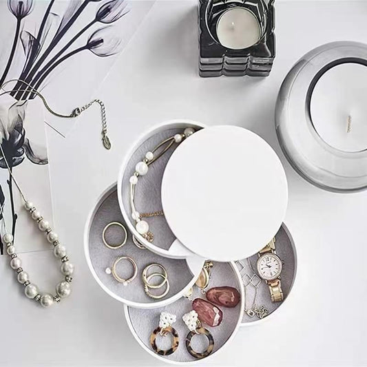 Rotating jewelry organizer with open circular lid showing dark velvet compartments for rings