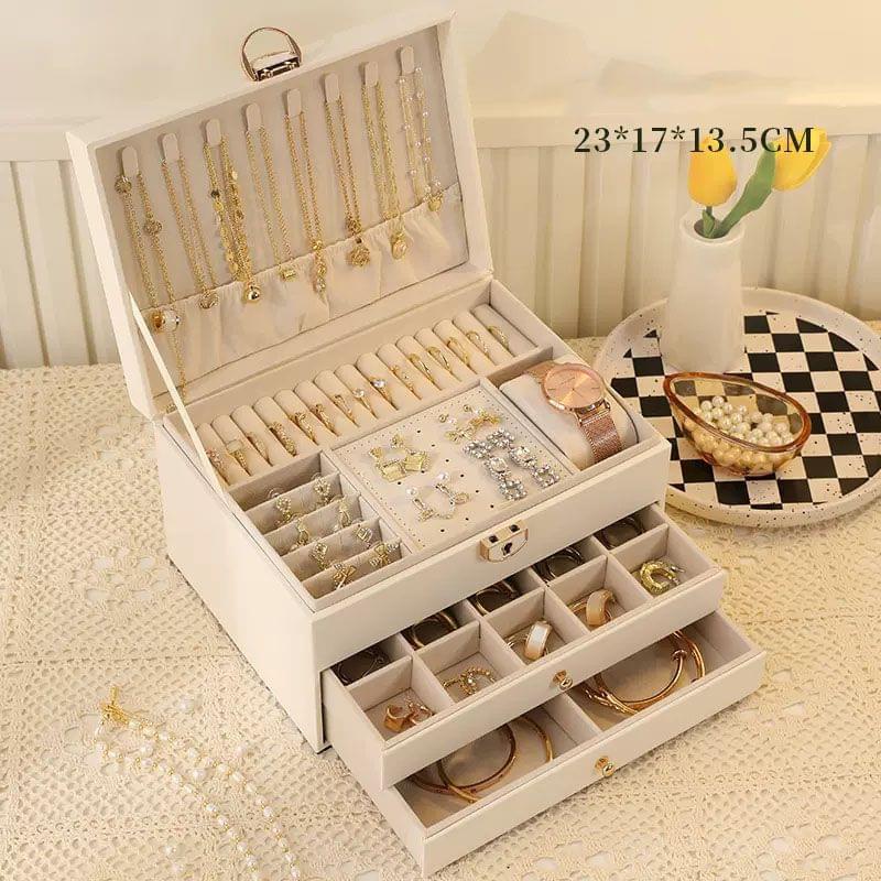 White lockable jewellery box open with necklace rows and stacked ring drawers on table