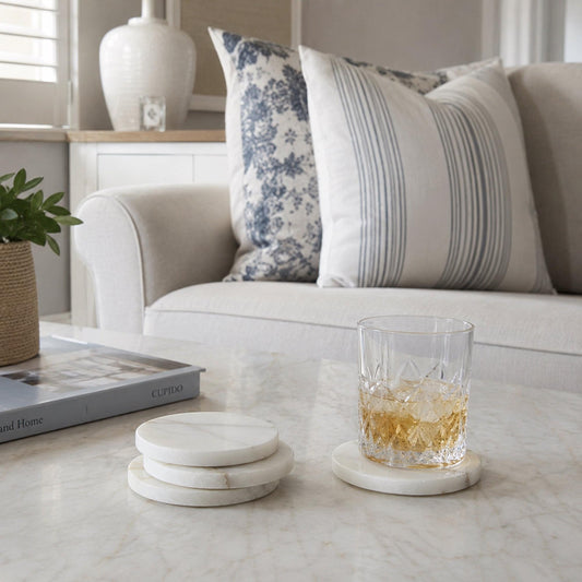 Alabaster-style coasters on a tabletop with a glass, round white stone set.