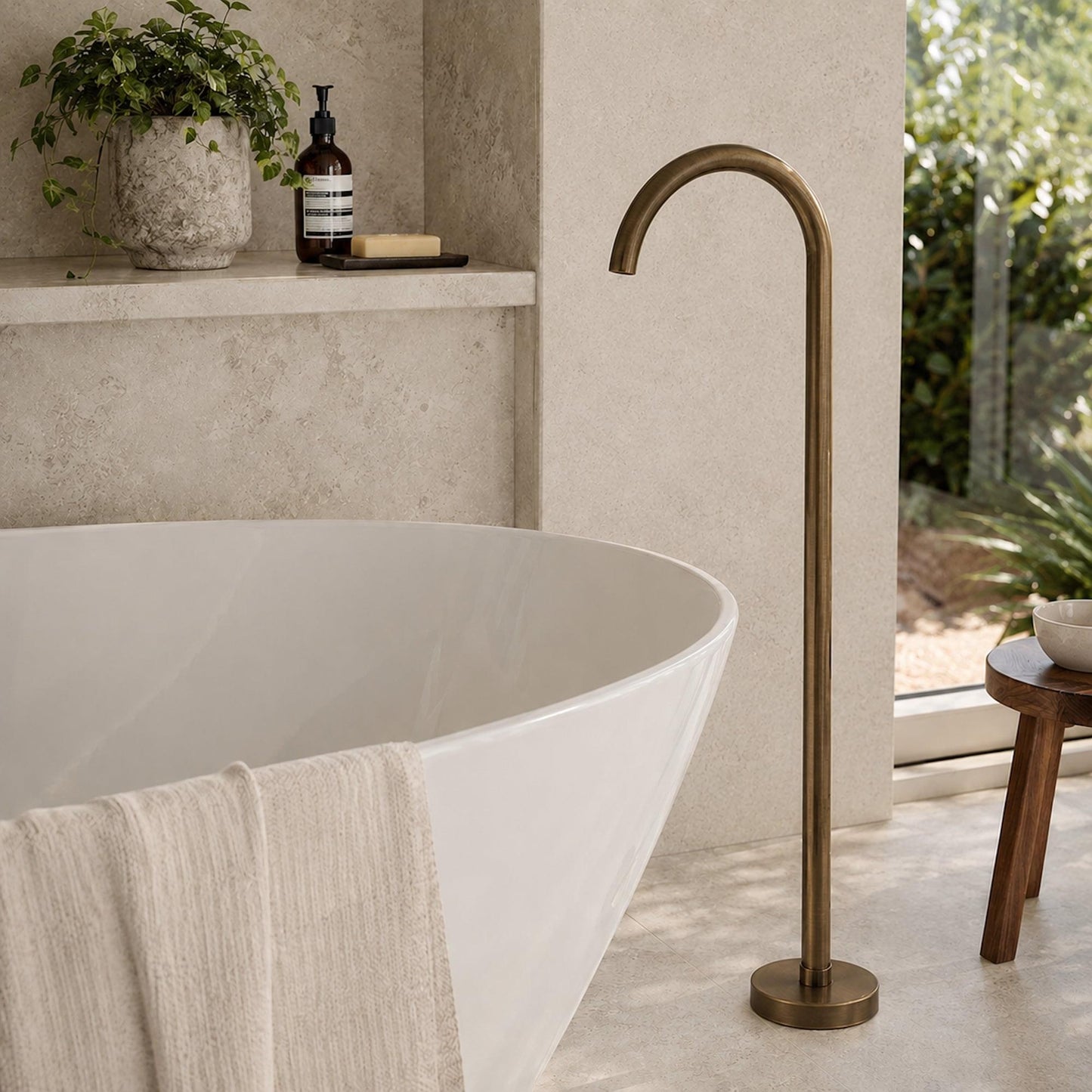 Freestanding bath spout in antique brass next to white oval tub