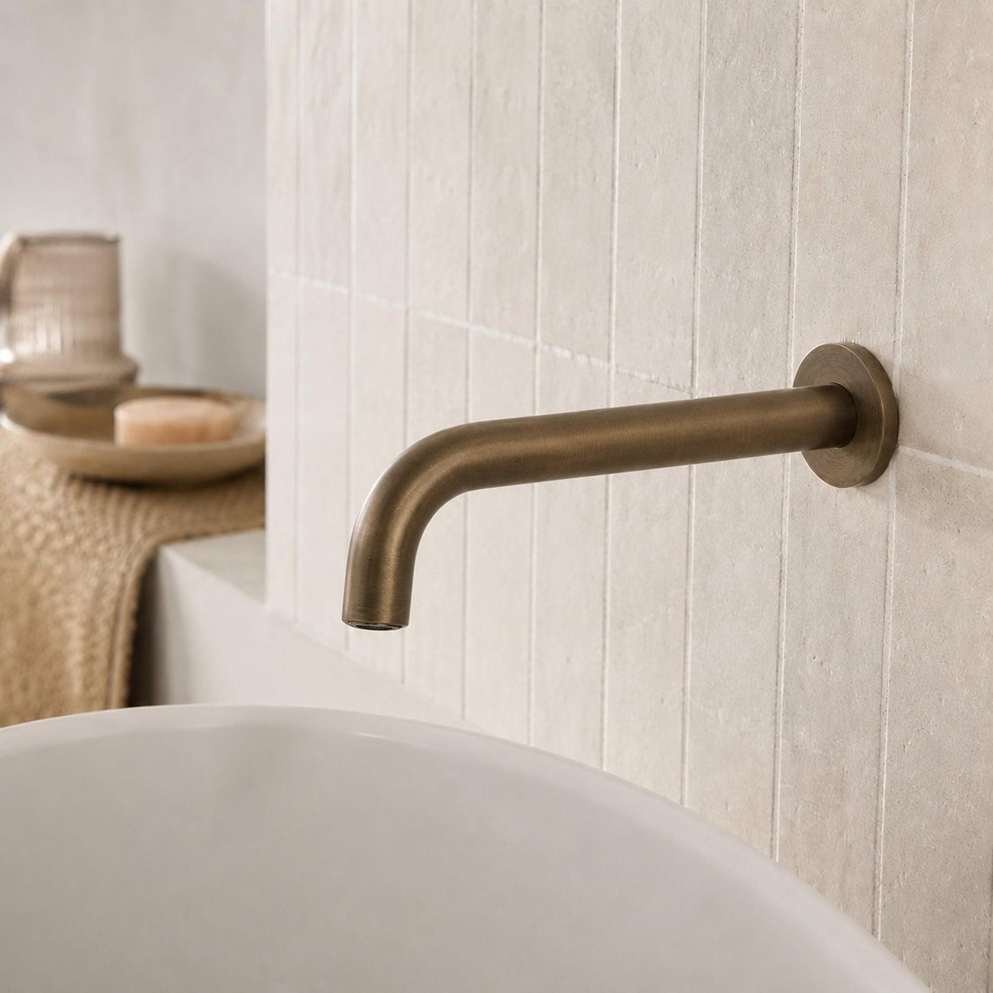 Antique brass curved wall spout mounted on tiled bathroom wall.