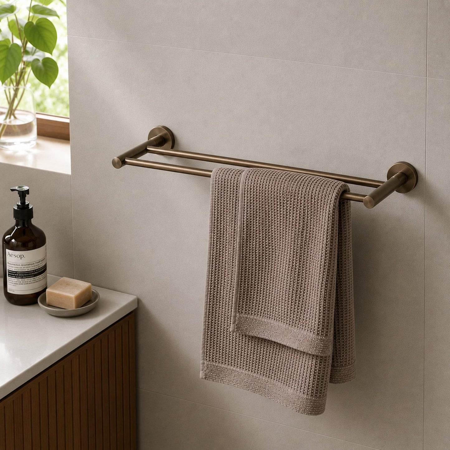 Antique brass double towel rail holding a folded gray bath towel on two bars