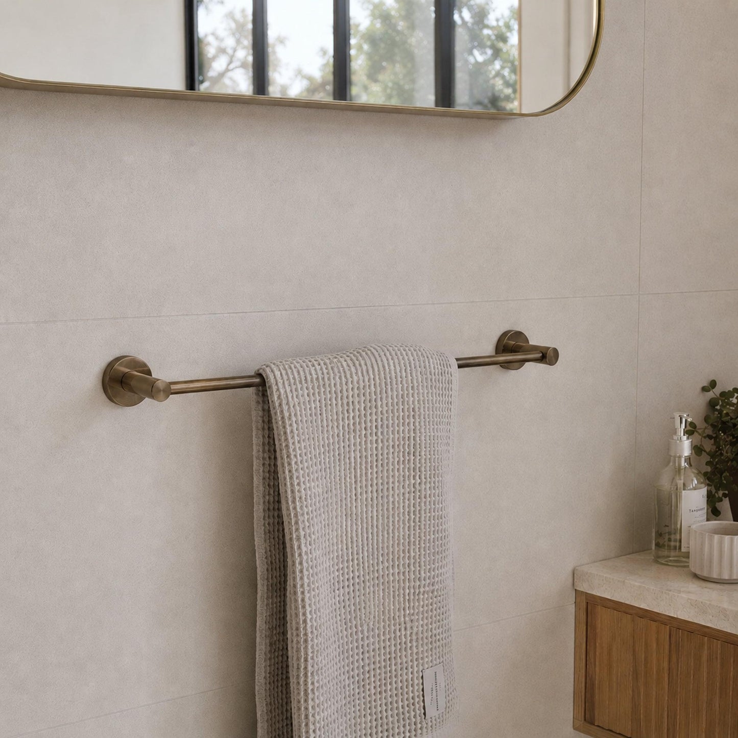 Wall-mounted antique brass towel rail with folded beige towel draped over the bar.