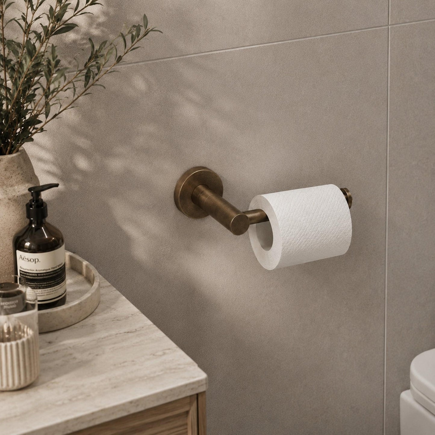Antique brass toilet roll holder holding a white paper roll on wall