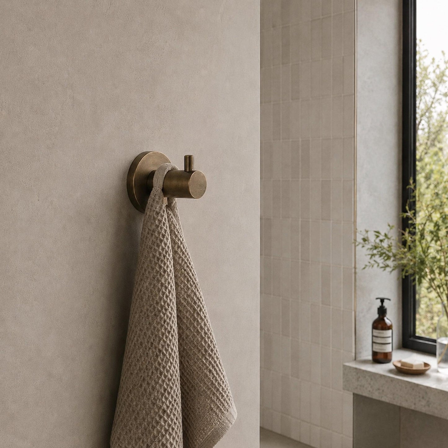 Reno robe hook, antique brass with textured towel hanging from the round arm
