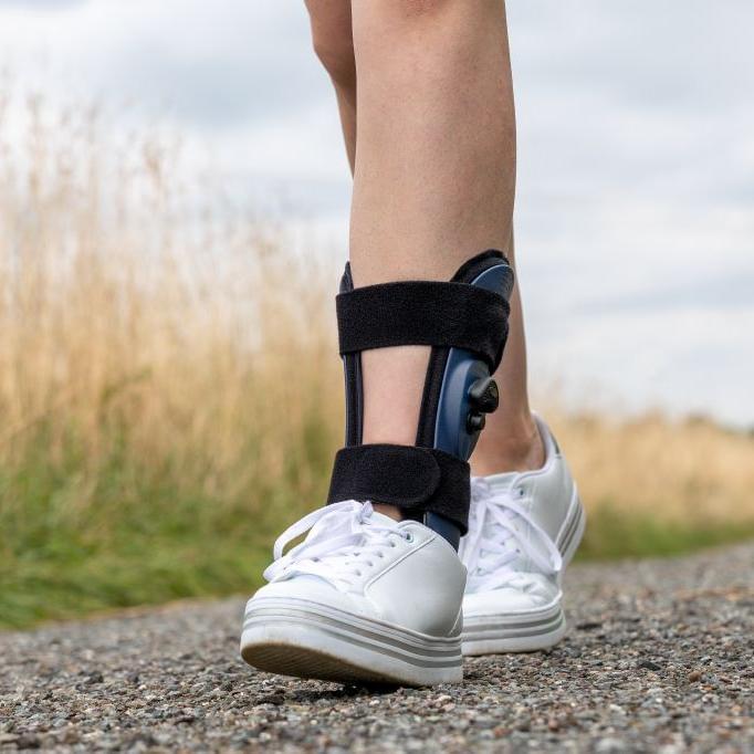 Ankle brace with black straps and blue-gray support with white sneakers