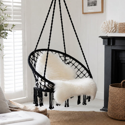 Black macrame hanging chair swing with curved net seat and white faux-fur cushion