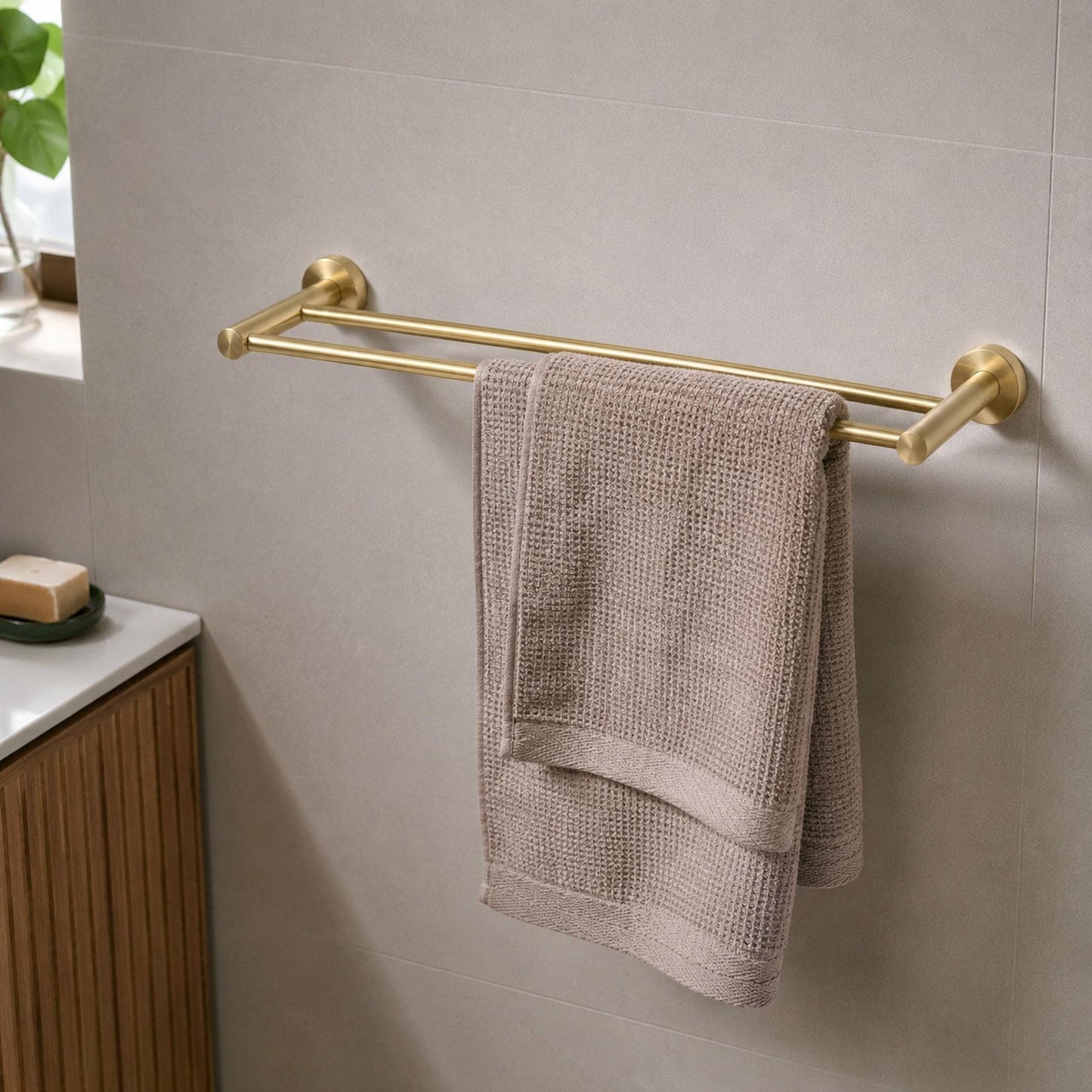 Brushed brass double towel rail holding a folded light towel