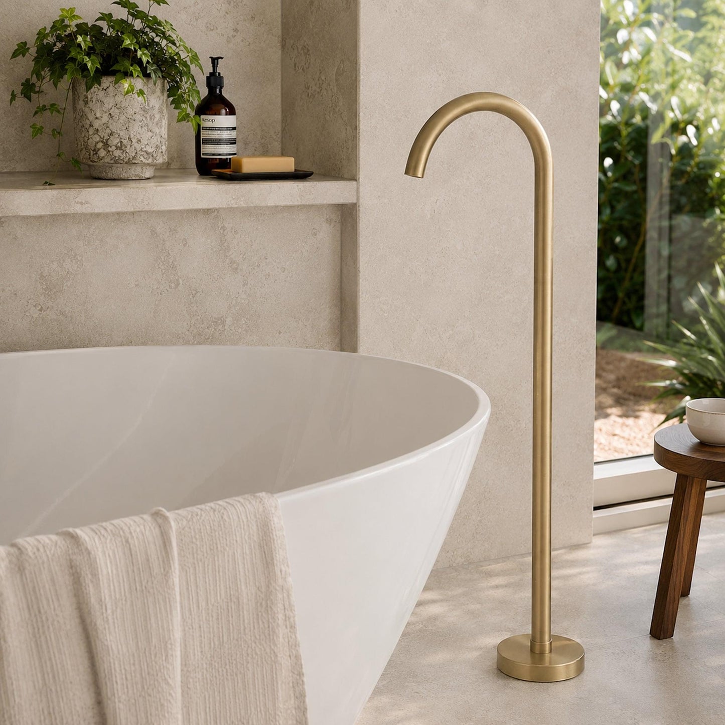 Freestanding bath spout in brushed brass with arched spout and round floor base