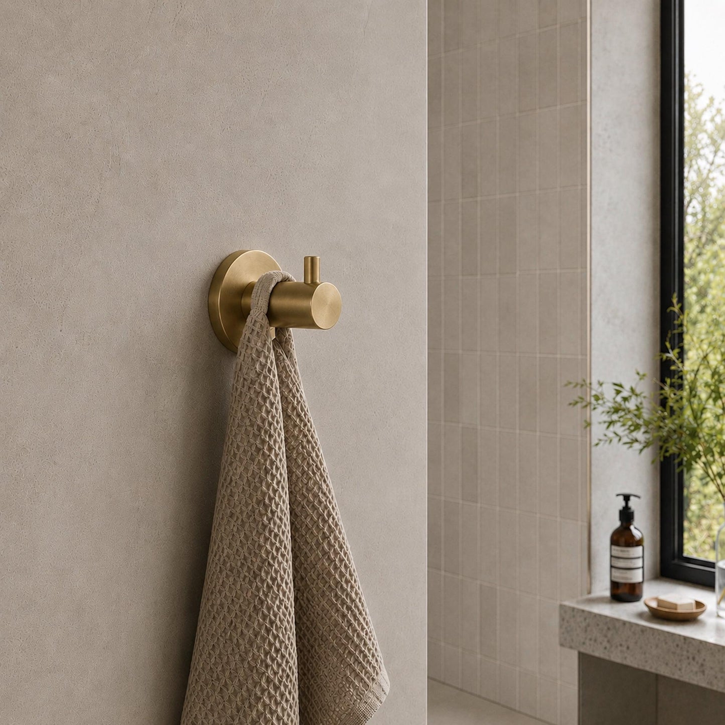 Brushed brass robe hook wall mount holding a hanging towel