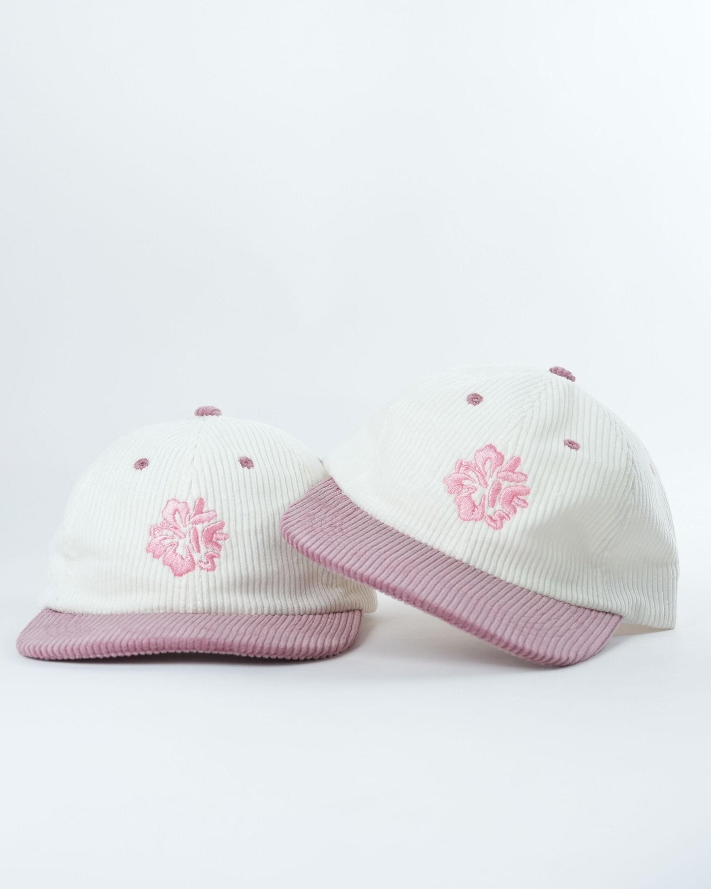 Cream knit beanies with pink floral embroidery and ribbed pink brims, two views