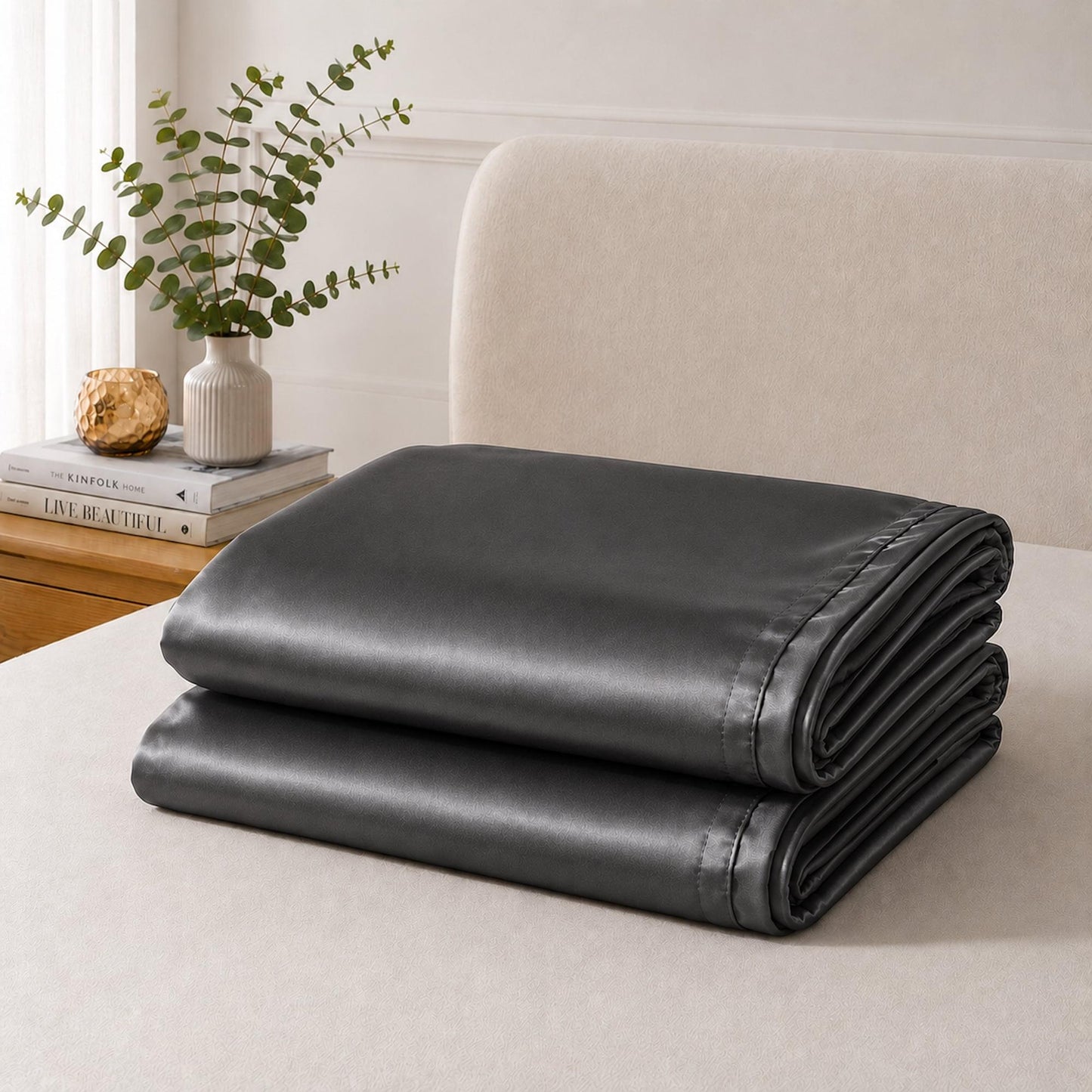 Folded charcoal satin pillowcase with envelope seam detail and smooth glossy surface.