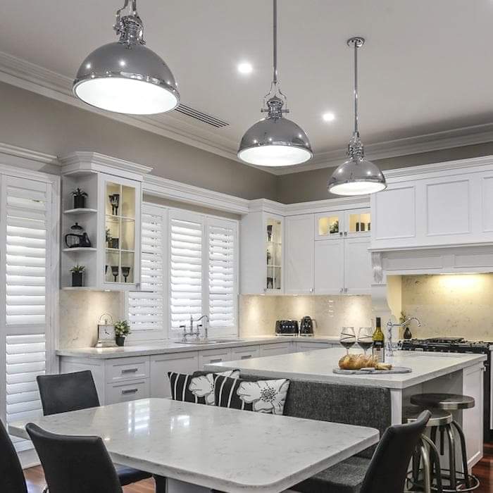 Chrome pendant lights with domed metal shades over kitchen island