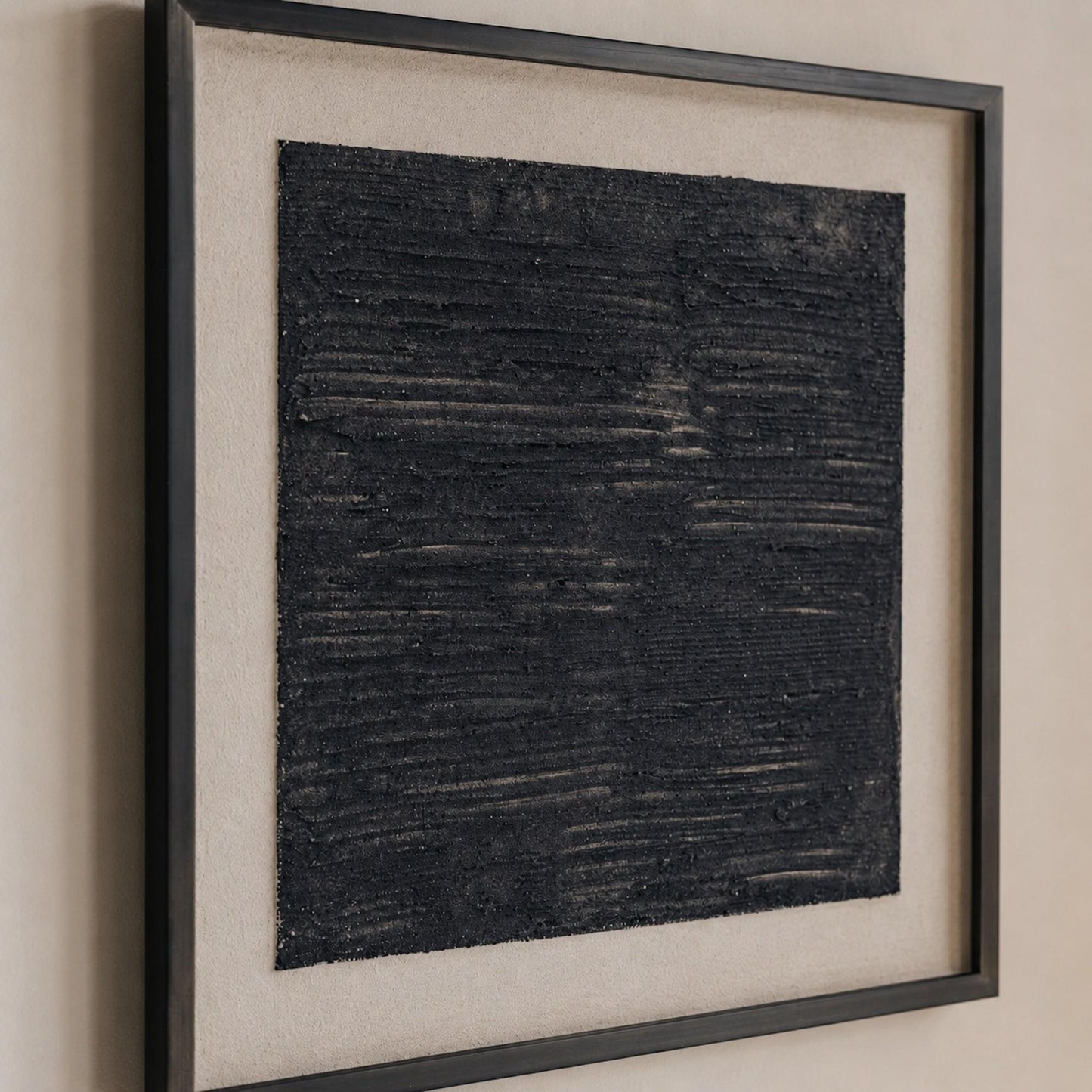Close-up of framed dimensional sand art with dark blue textured, grainy finish
