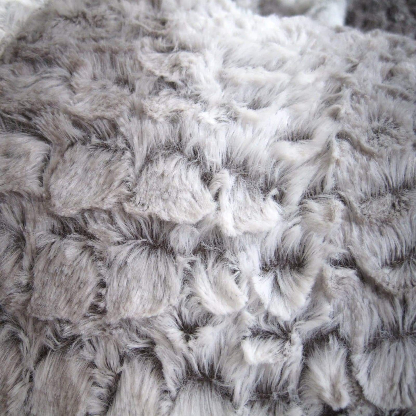 Silver gray faux fur bean bag fabric close-up with dense mottled texture