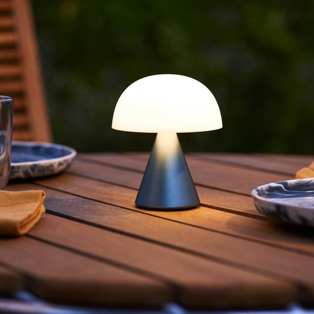 Portable LED lamp glowing on outdoor wooden table
