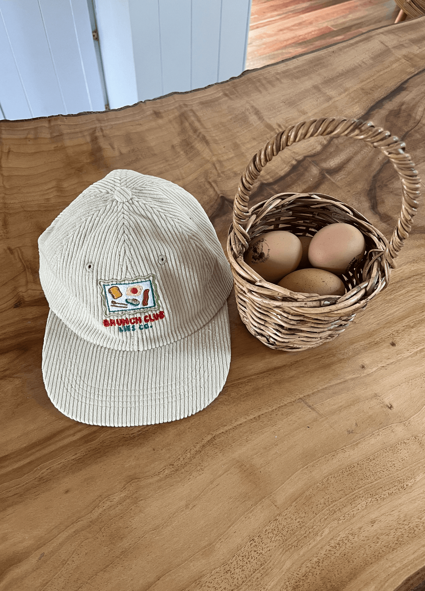 Light beige ribbed cap hat with front logo patch on wooden surface