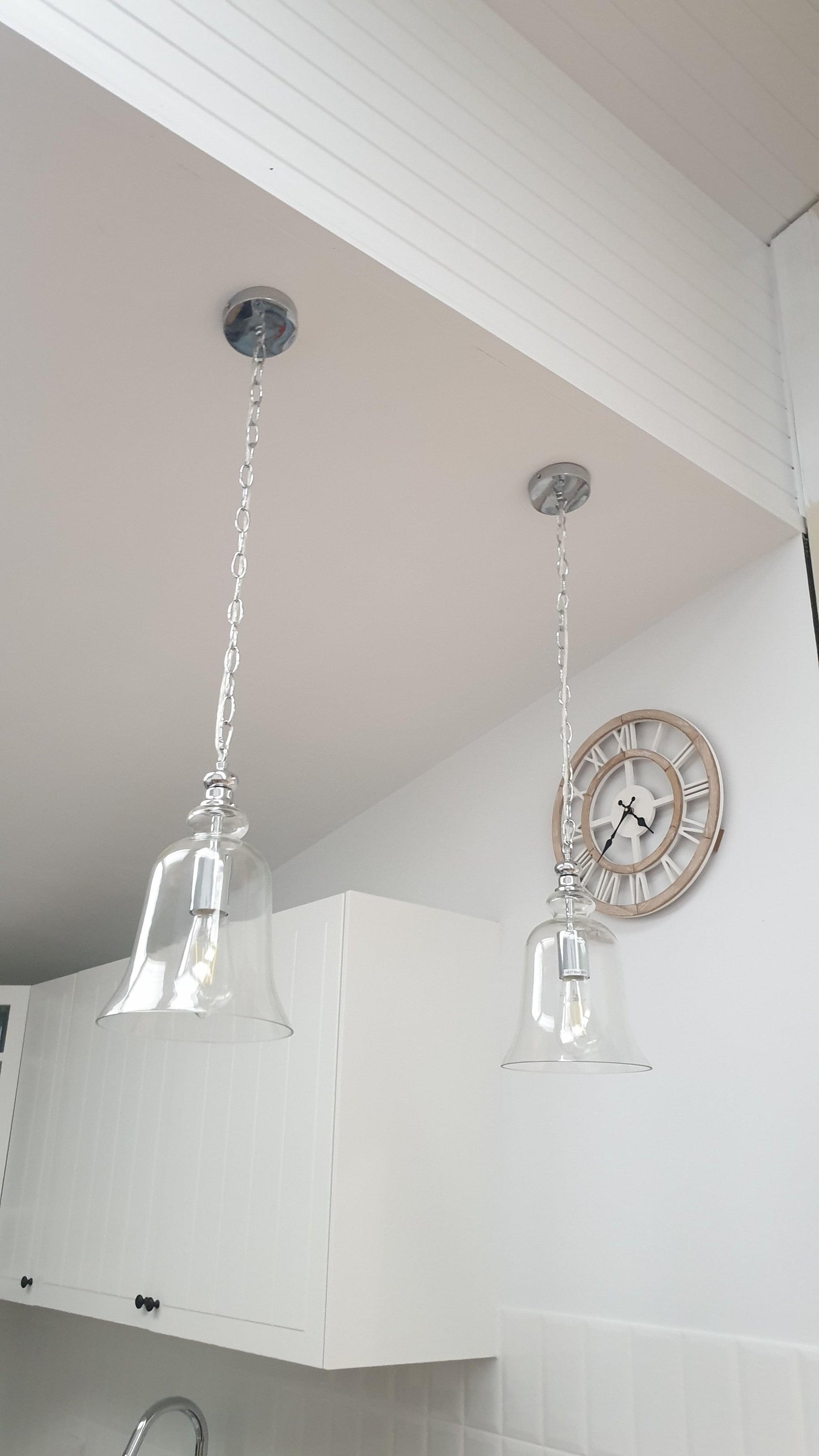 Clear glass bell pendant light with polished chrome top and long metal chain