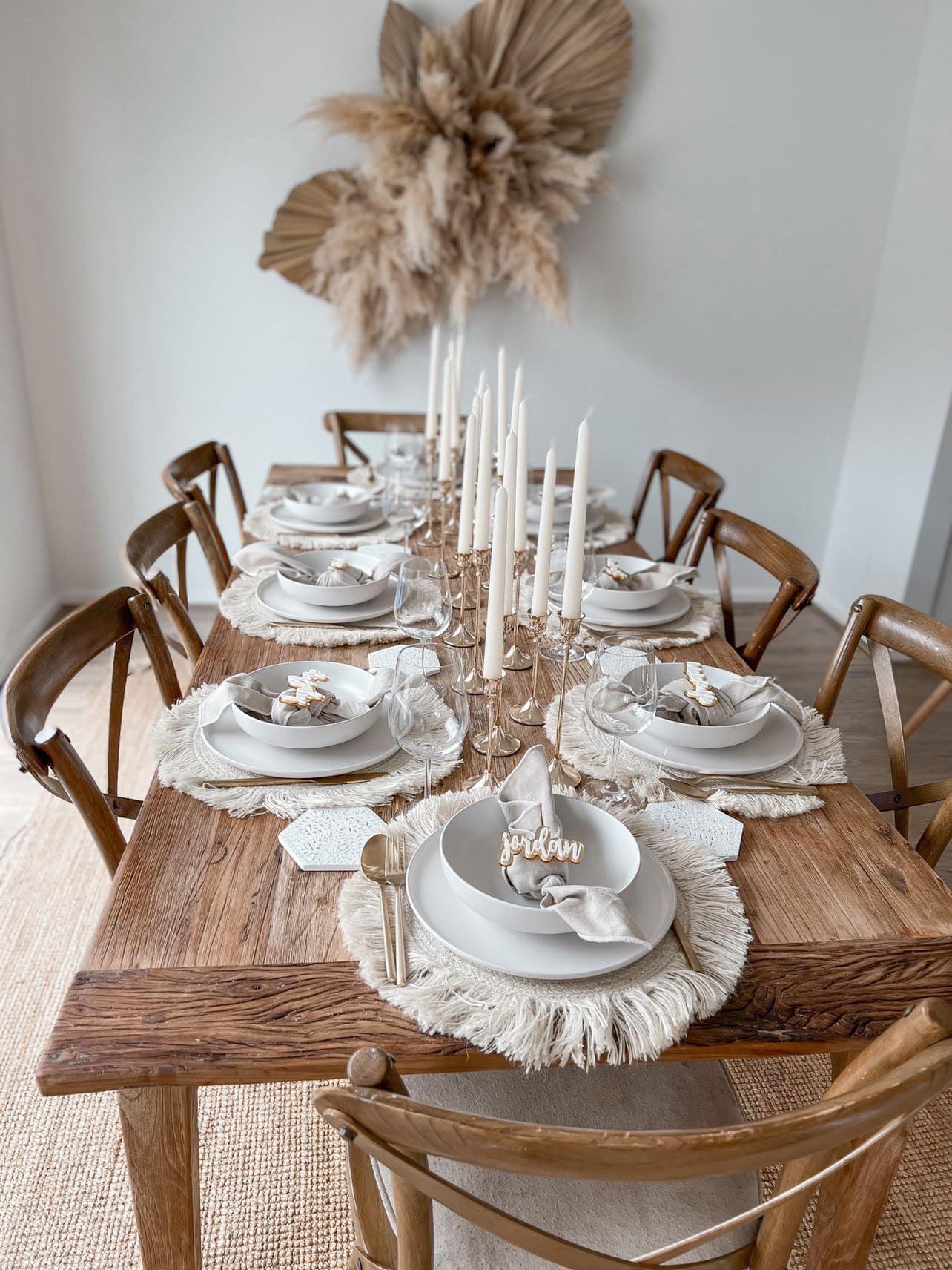 Rose-gold taper candlestick set with three tall holders and white candles on a dining table