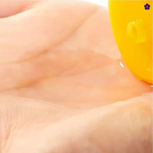 Yellow vitamin C lotion applied to skin in close-up, Melano CC