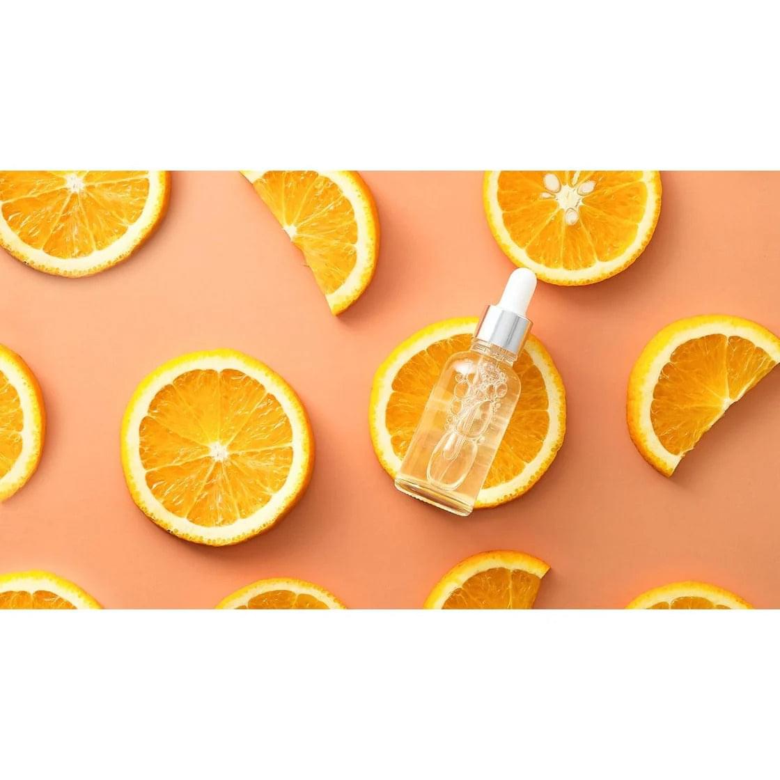 Small dropper serum bottle with clear liquid among orange slices