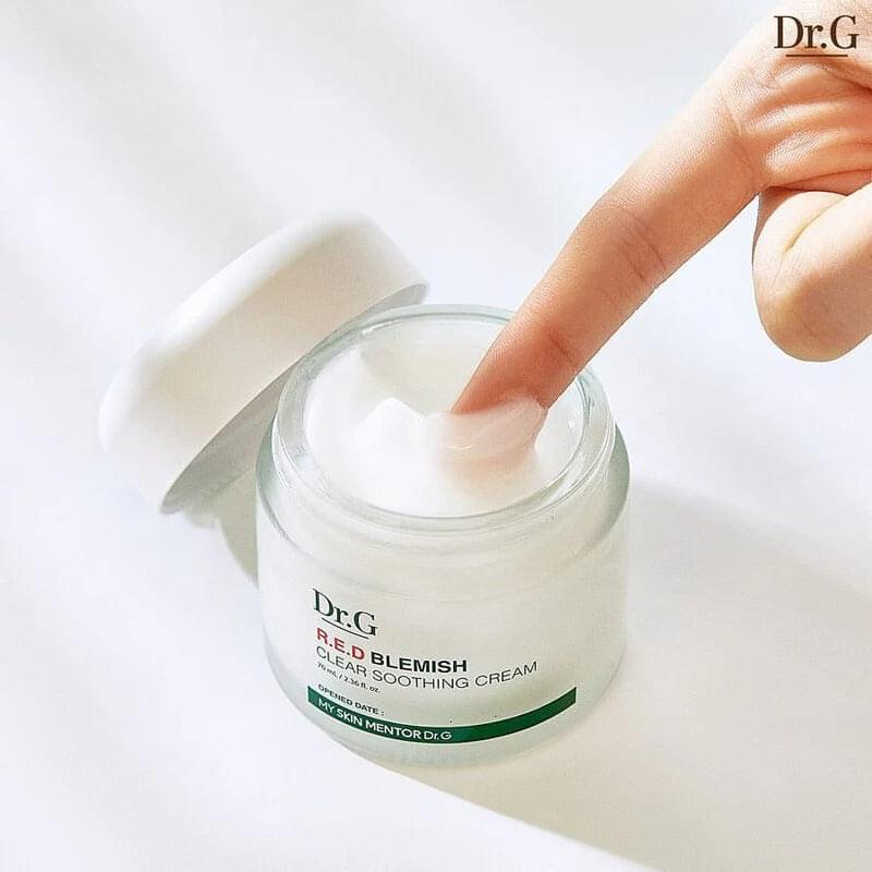 Hand scooping white cream from Dr.G R.E.D Blemish clear soothing cream jar