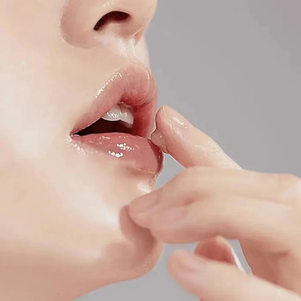 Applying lip essence to lips with fingers for a glossy, dewy finish